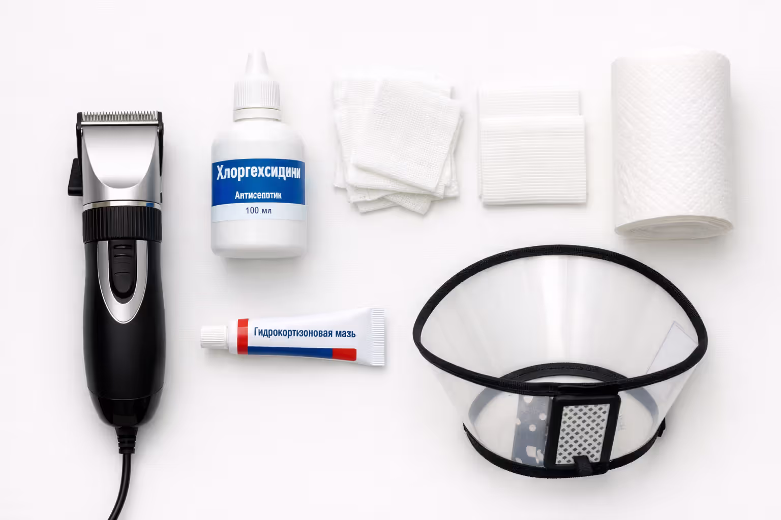 Flat lay of hot spot home treatment supplies including clippers, chlorhexidine, gauze, hydrocortisone cream, and an Elizabethan collar