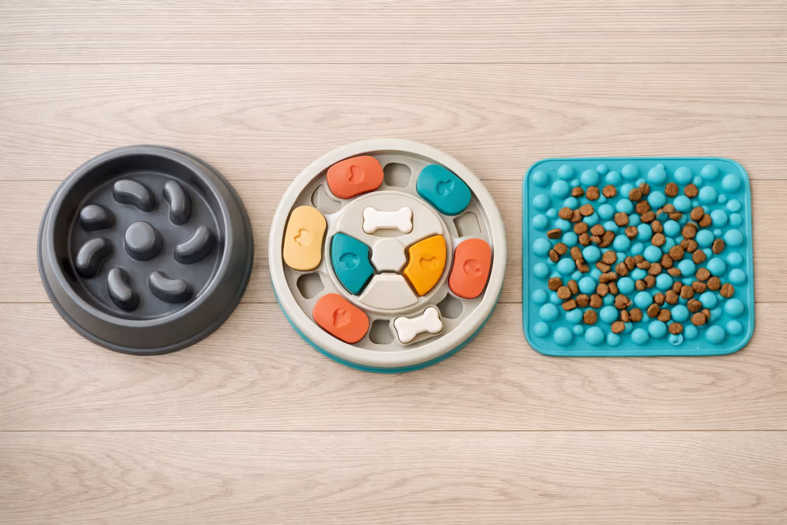 Three types of slow-feed dog bowls — ridged bowl, puzzle feeder, and snuffle mat with kibble scattered on it